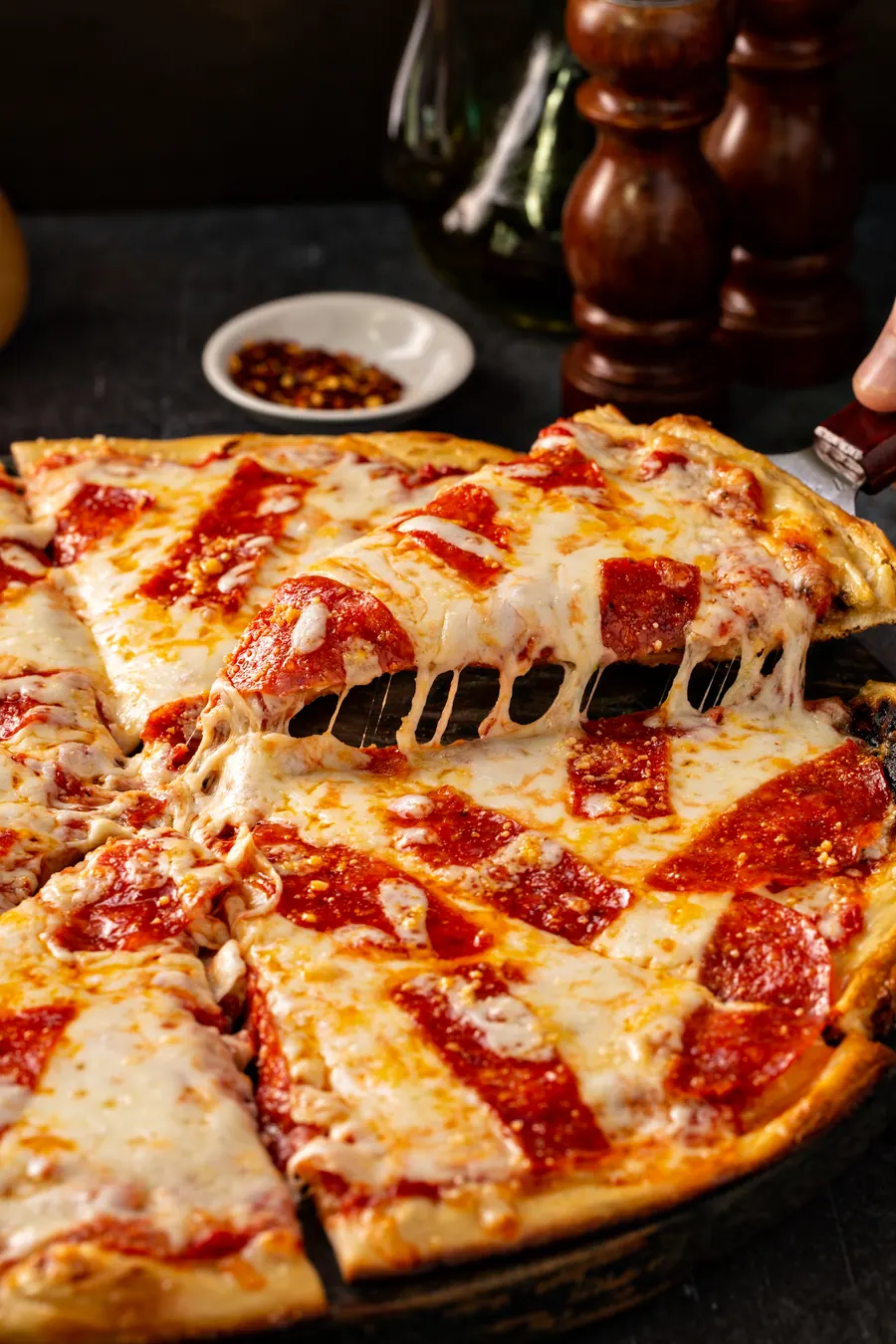 Parče pizze sa rastegnutim sirom podignuto sa tacne